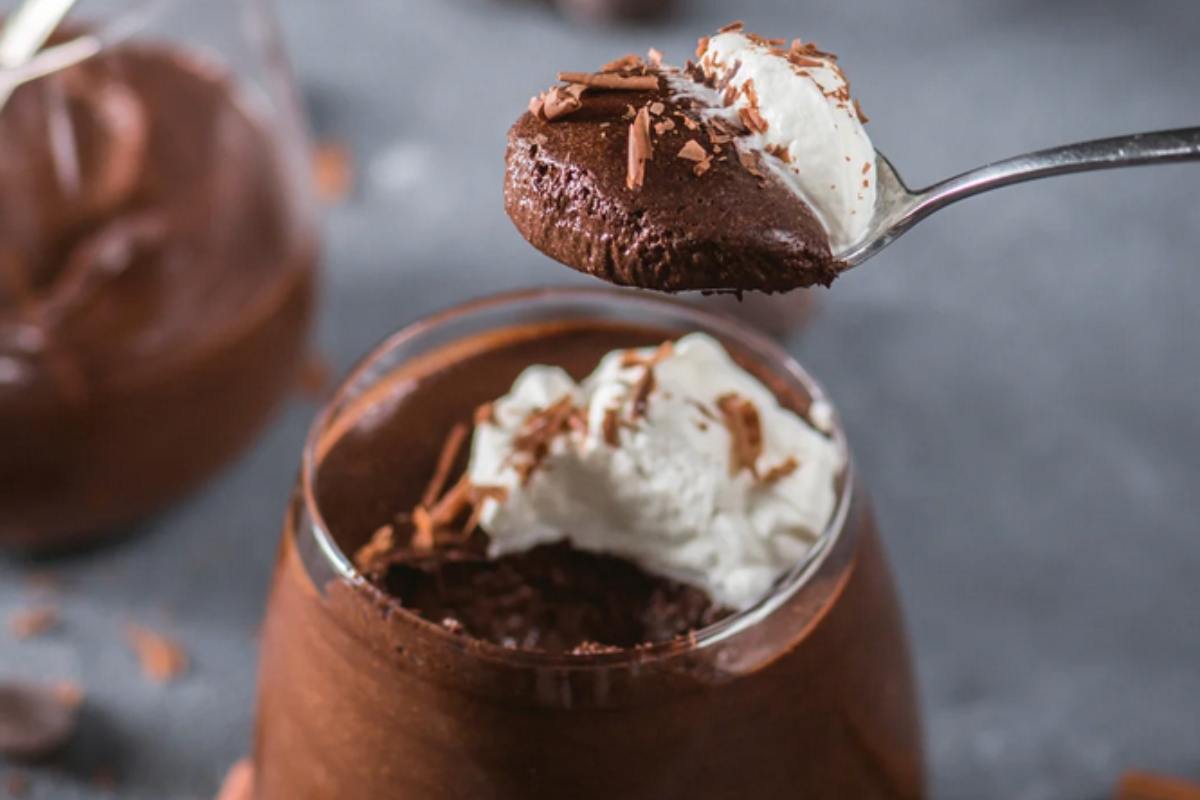 Vasetto con torta al cioccolato e panna e cucchiaino con un boccone abbondante