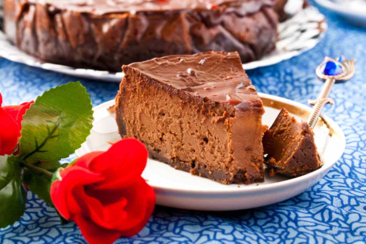 fetta di torta al cioccolato su un piatto e accanto una rosa rossa