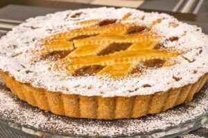 crostata intera con zucchero a velo in un vassoio