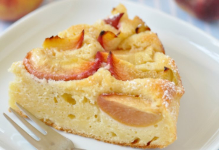 fetta di torta alle pesche su un piatto con accanto una forchetta