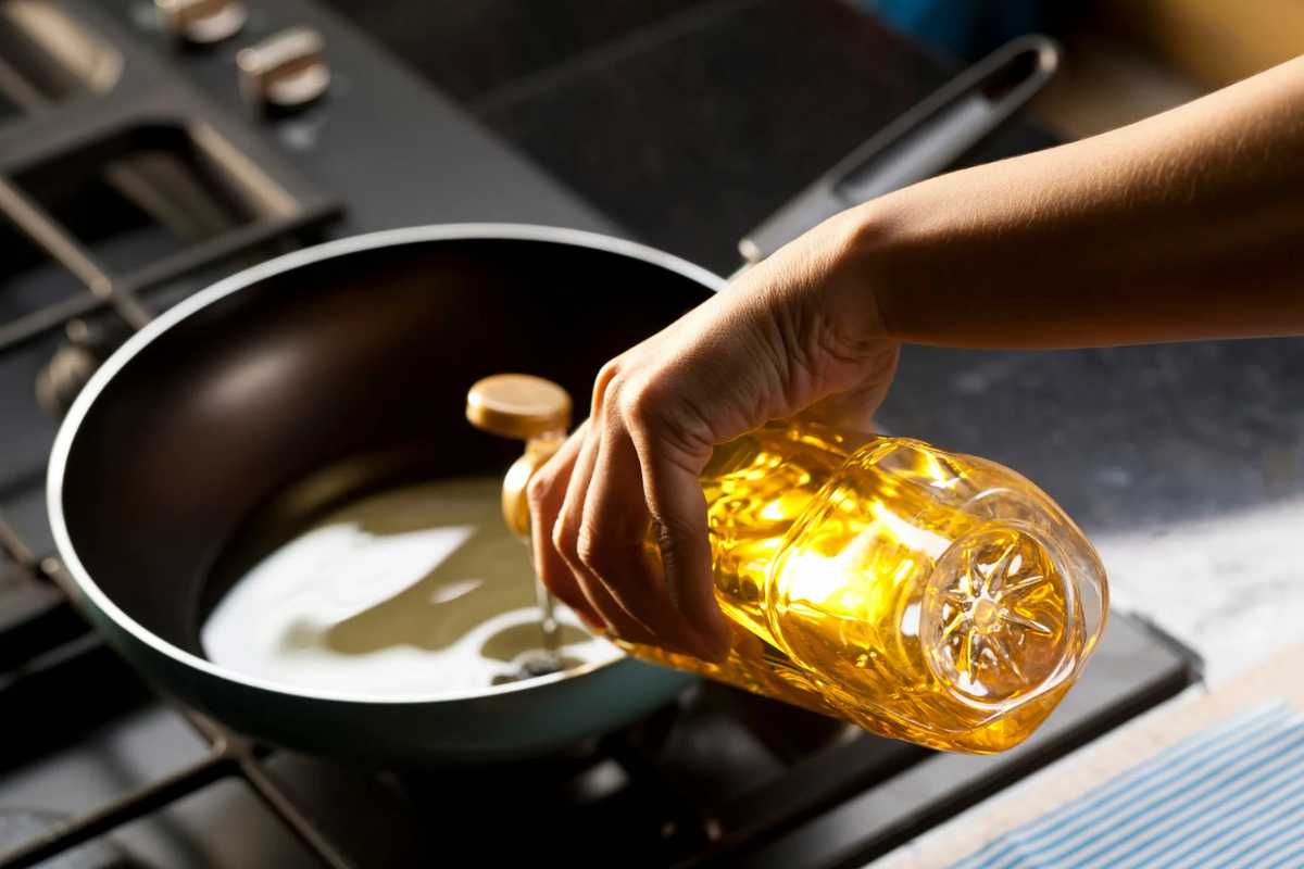 Persona che versa olio in una padella