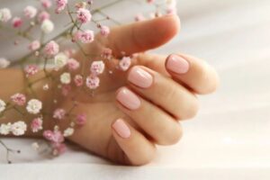 unghie rosa accanto a dei fiori