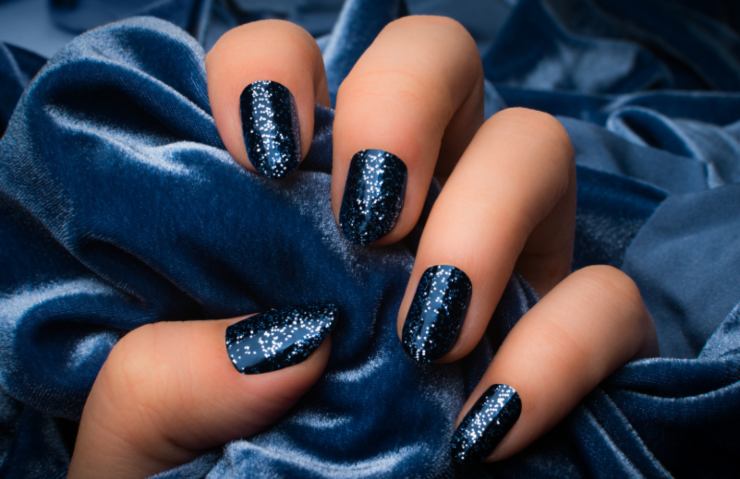unghie con smalto scuro con brillantini