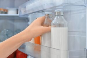 mano prende bottiglia di latte dal frigo