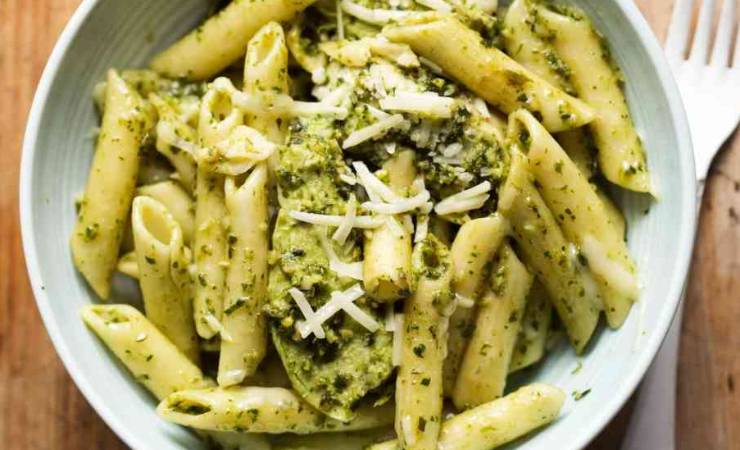Piatto pieno di pennette al pesto e formaggio