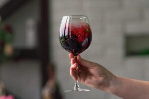Persona che tiene in mano un bicchiere di vino rosso