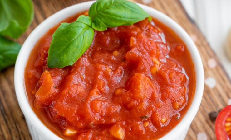 Ciotola con salsa di pomodoro e foglie di basilico