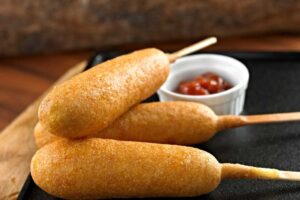 Tre wurstel panati con stecchino e salse accanto
