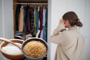 Donna che guarda nell'armadio con una mano sul viso, una ciotola di sale e una ciotola di riso