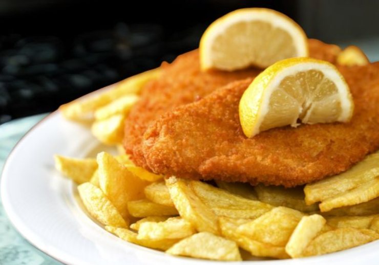 cotolette impanate e fritte sopra un letto di patatine fritte