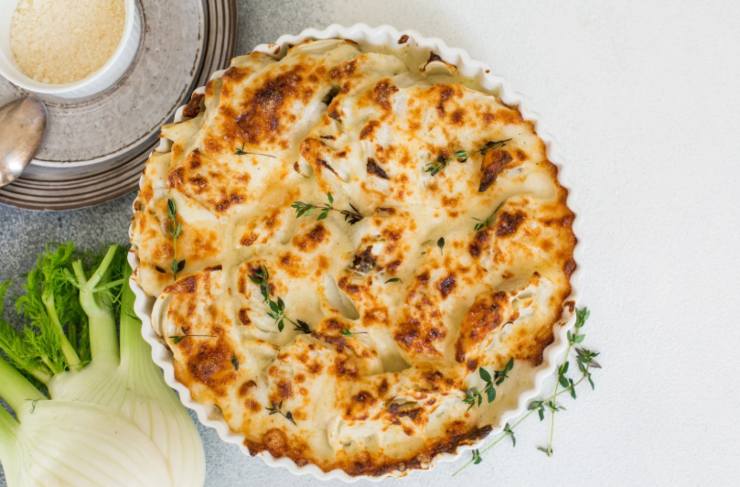 gratin di finocchi e accanto un finocchio crudo