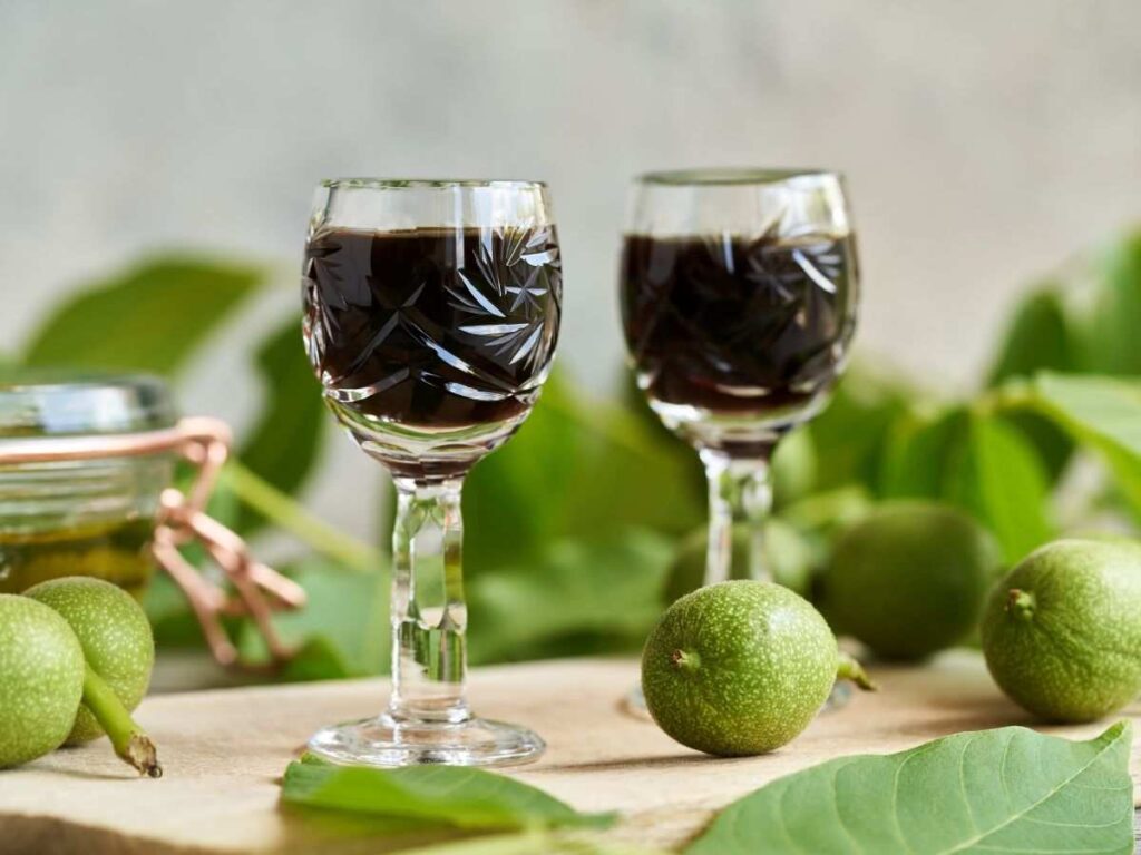 liquore alle noci dentro bicchierini con malli intorno