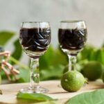 liquore alle noci dentro bicchierini con malli intorno