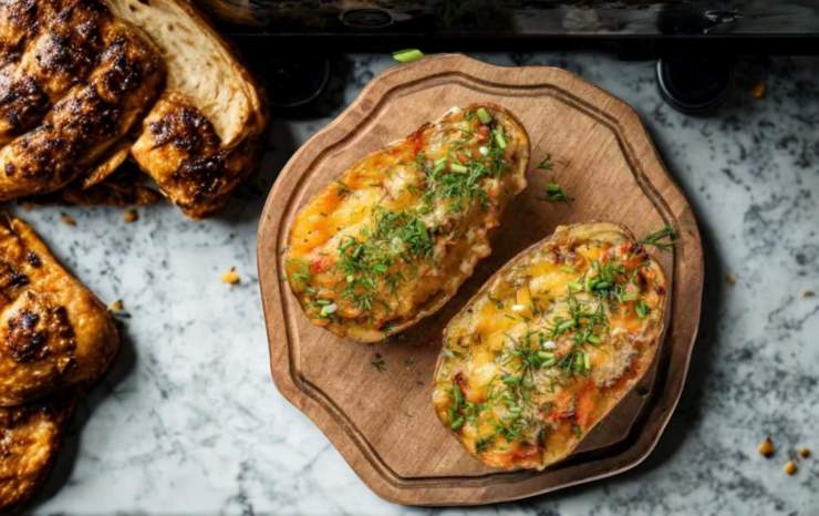 patate ripiene su un tagliere di legno sul tavolo della cucina