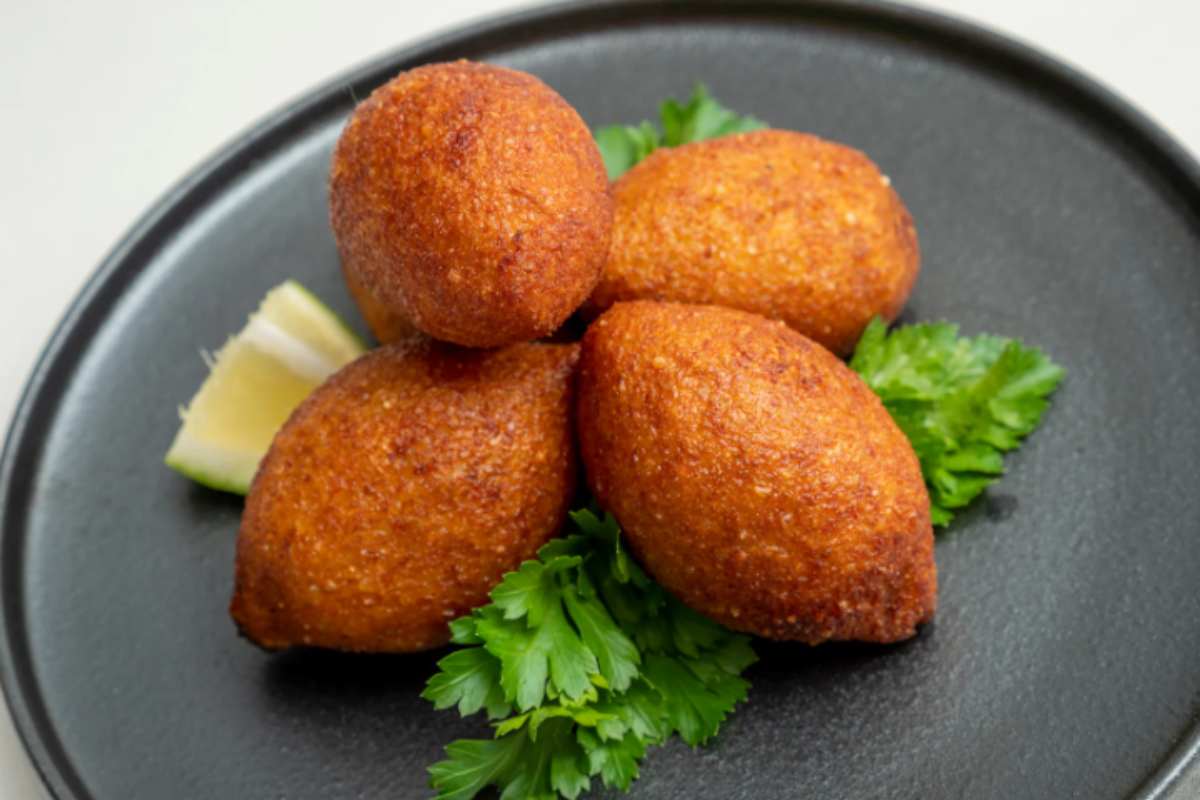 crocchette fritte su un piatto sopra ad un letto d'insalata con accanto una fetta di limone