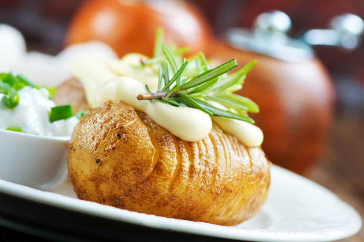 Patata a fisarmonica con salsa e rosmarino in un piatto