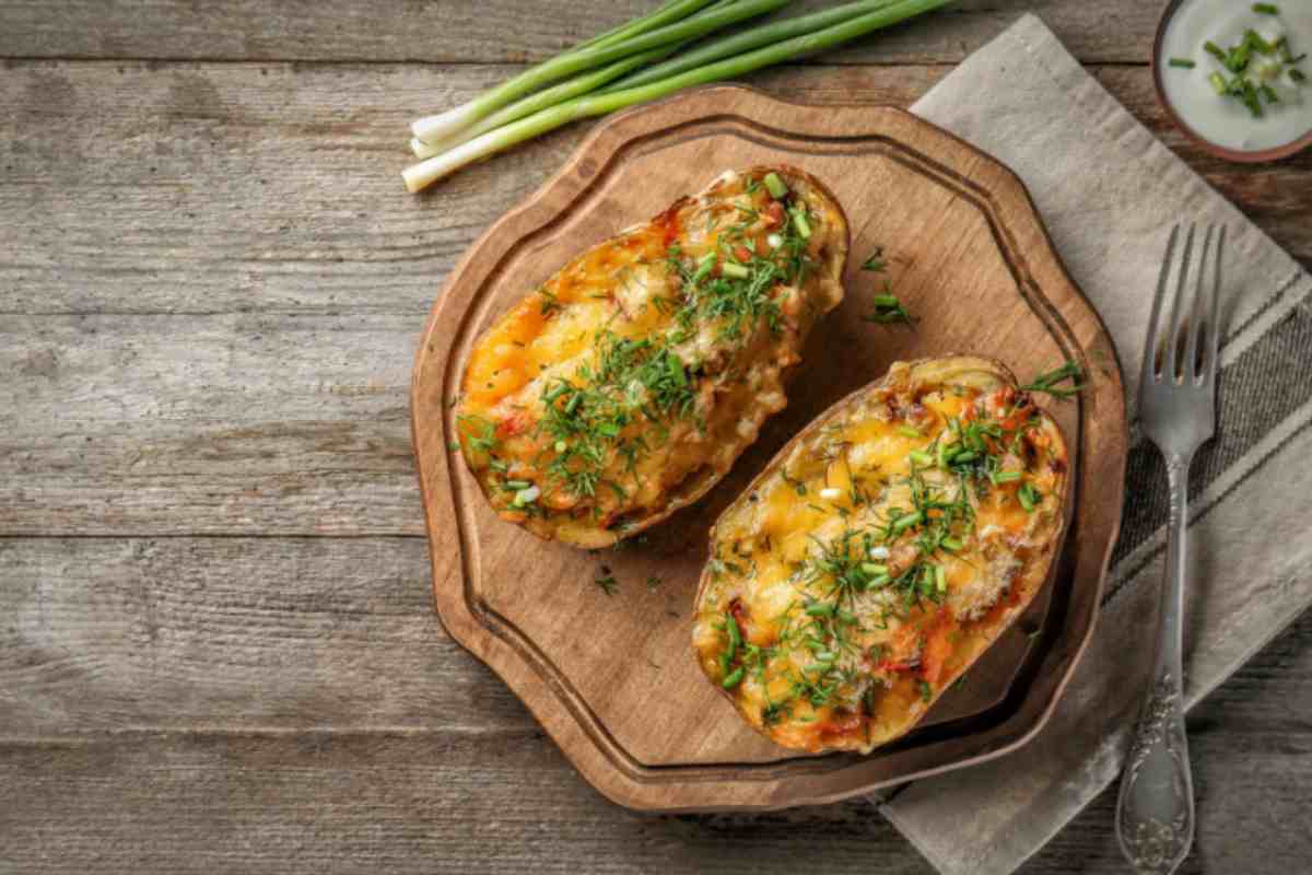 due patate ripiene cremose su un tagliere di legno