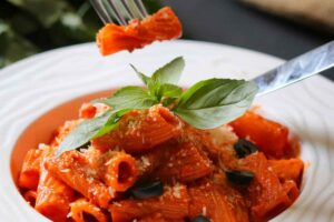 Piatto con rigatoni al sugo e foglie di basilico