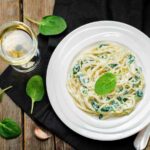 spaghetti in un piatto conditi con ricotta e spinaci freschi