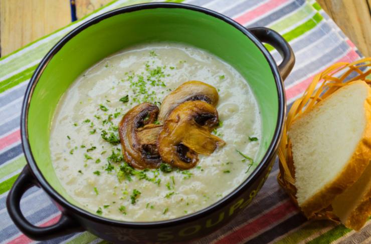 vellutata con sopra dei funghi e accanto delle fette di pane